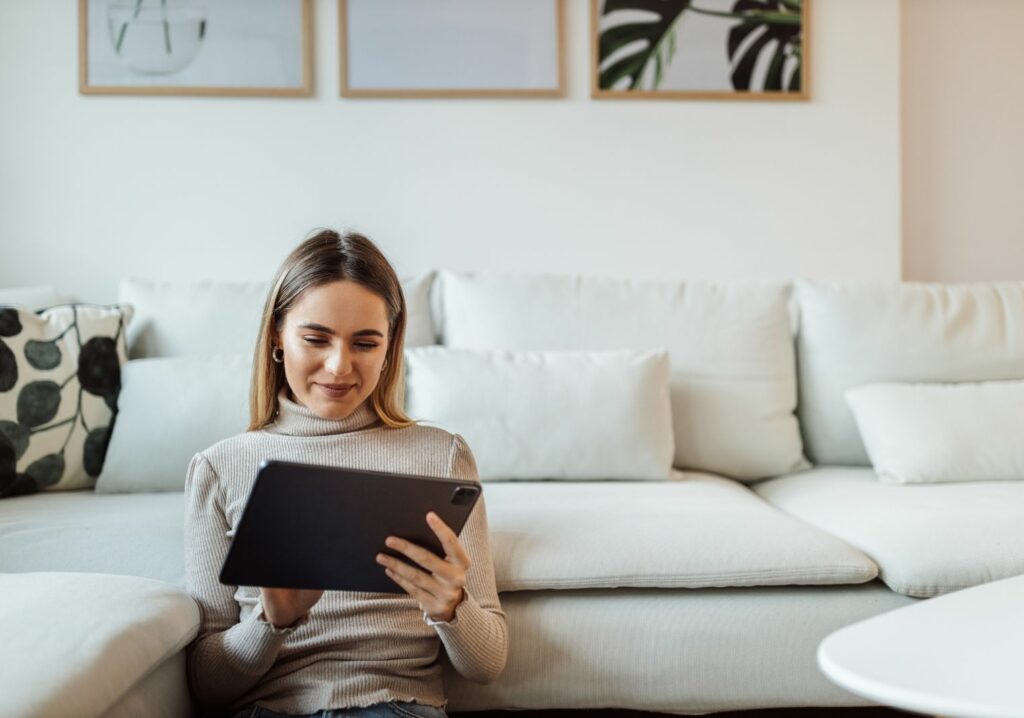 A woman smiling and looking at a tablet